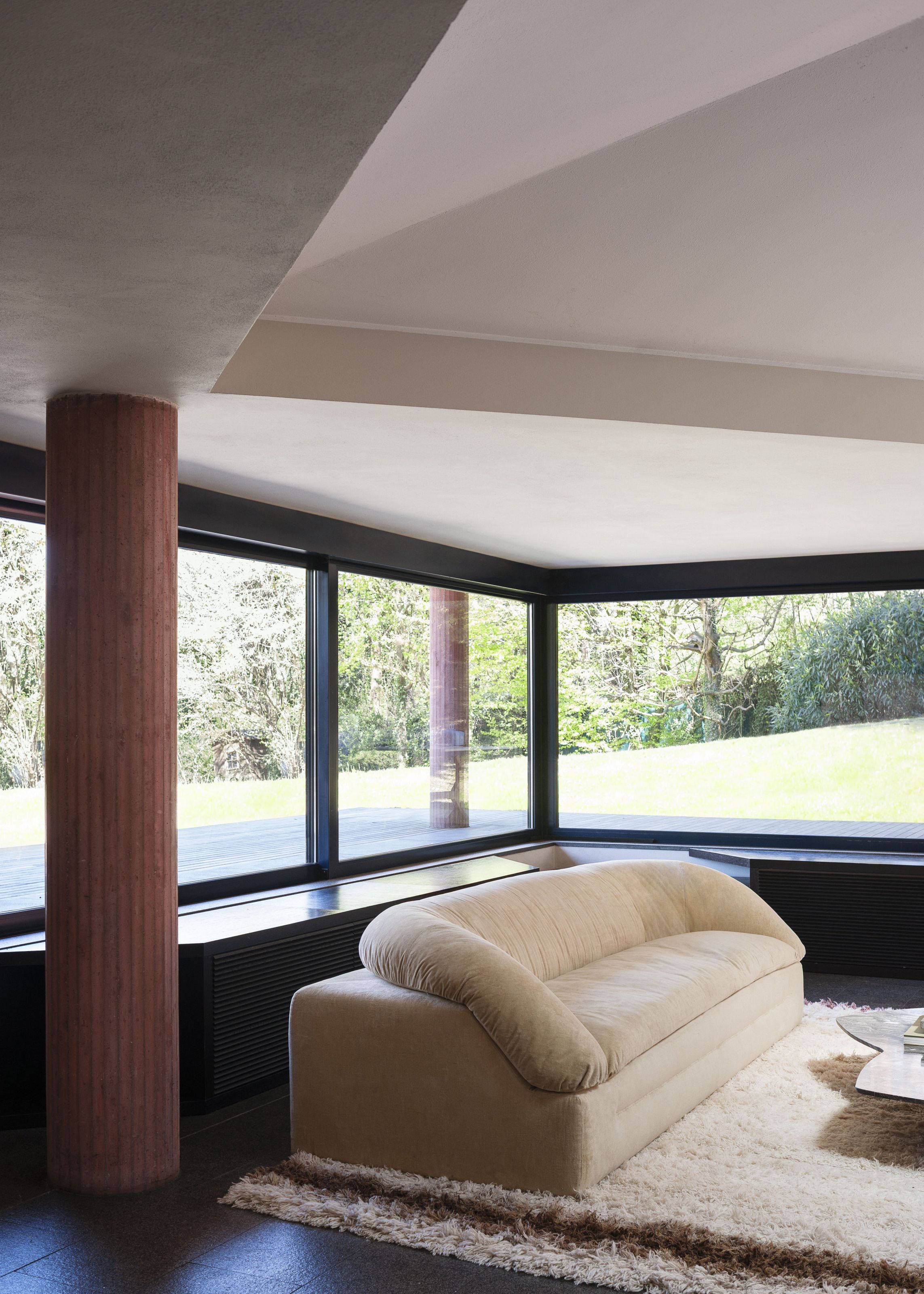 Butter sofa in a modernist interior with warm timber and stone